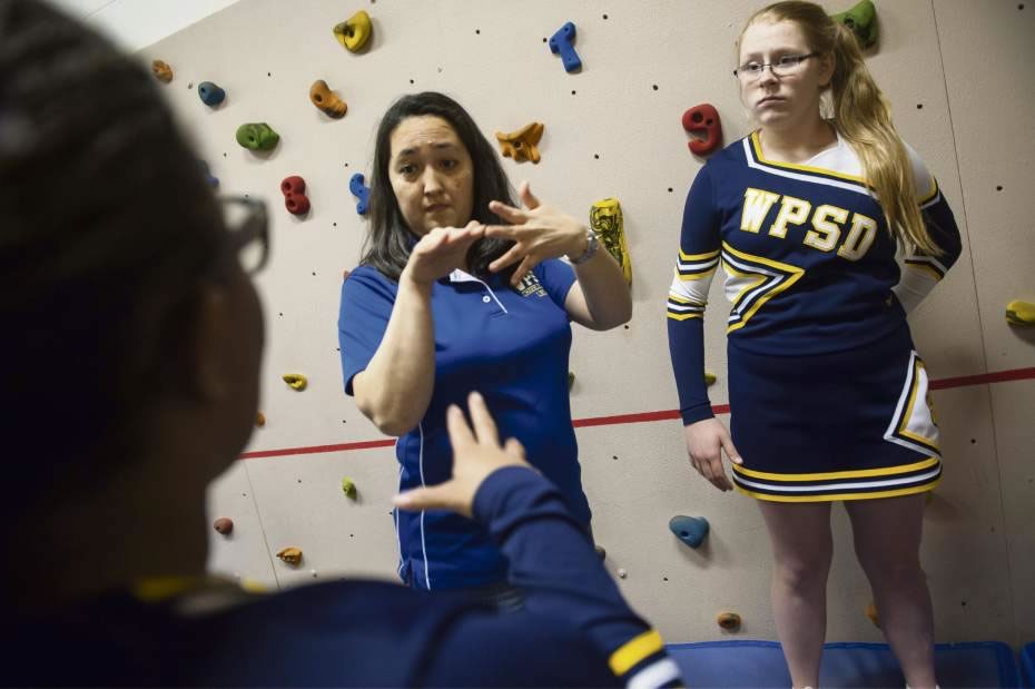 Cheerleading coach Linda Langer, center, signs to Rebekah Quinn, right, and other members of Western Pennsylvania School for the Deaf's cheerleading team as they warm up to cheer for a home basketball game at the Edgewood school's gym on Thursday, Feb. 4, 2016. Photo by Stephanie Strasburg, Tribune-Review