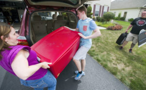 Mother Karin Davies, left, helps Bradley Speck load a large container while his stepfather, Ashley Davies, right, brings more items from the house. Speck's family accompanied him to Rochester, N.Y., to help him move into a dorm at the National Technical Institute for the Deaf, a college of the Rochester Institute of Technology. (Paul Kuehnel — Daily Record/Sunday News)