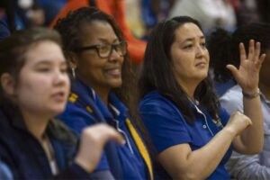 Cheerleading coach Linda Langer, left, and assistant coach Venita Smith, center, sign to members of Western Pennsylvania School for the Deaf's cheerleading team across the court during a home basketball game at the Edgewood school's gym on Thursday, Feb. 4, 2016. Also pictured is Dennita Lewis, cheering from the bleachers, pictured far left.